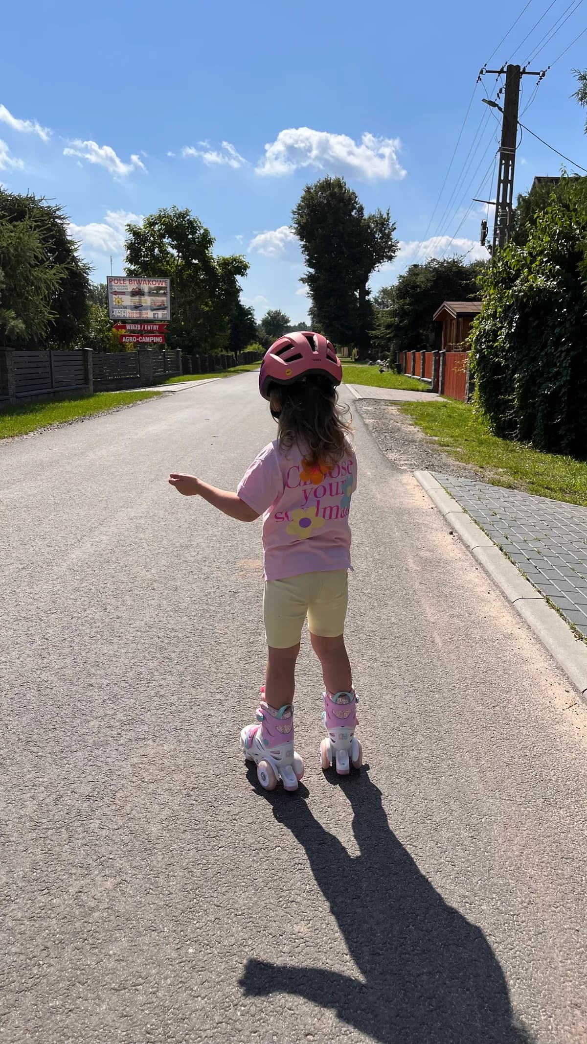 Dziewczynka w kasku jedzie na rolkach wiejską ulicą